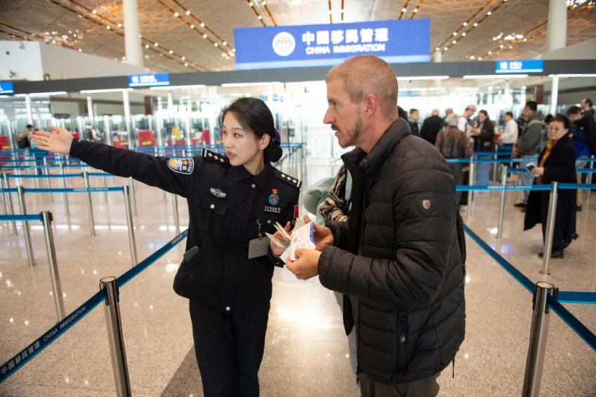 A border inspection officer assists a foreign tourist at Beijing Capital International Airport's Terminal 3 on Dec 4. Xinhua